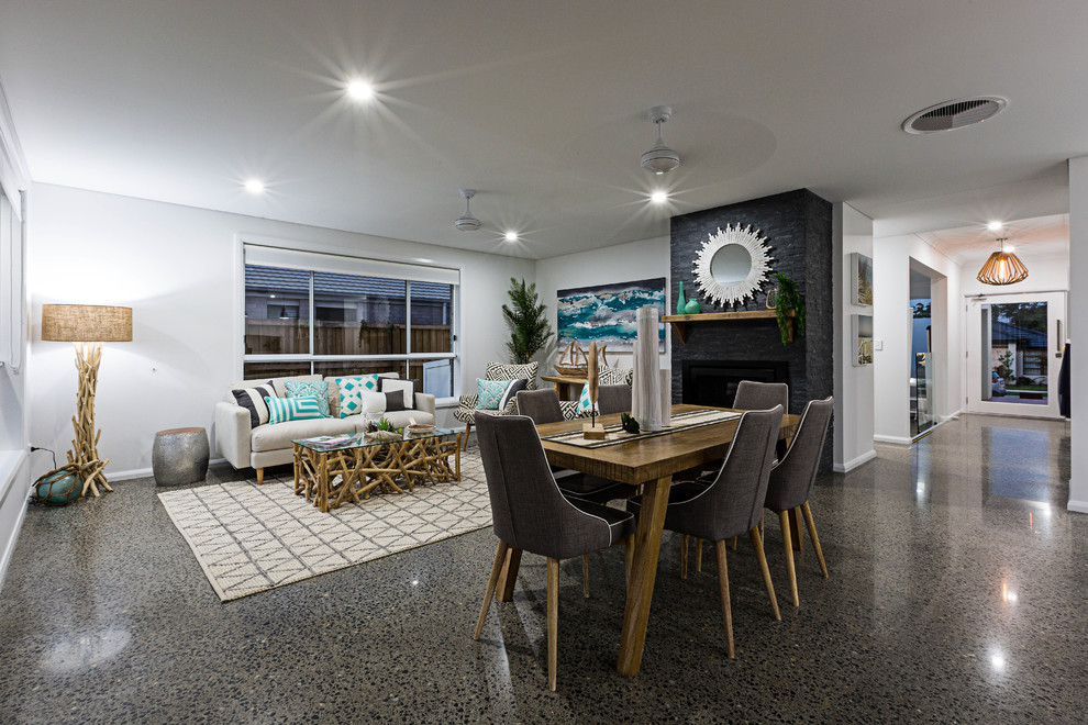 Immagine di una grande sala da pranzo aperta verso il soggiorno stile marino con pareti bianche e pavimento in cemento