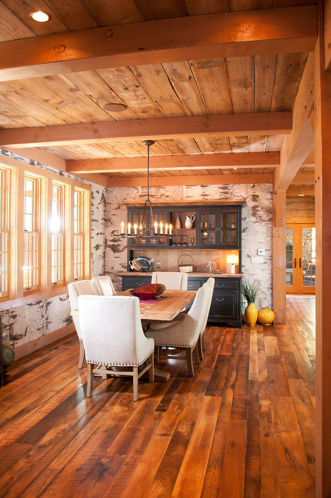 Cette photo montre une salle à manger ouverte sur la cuisine montagne de taille moyenne avec un mur multicolore et un sol en bois brun.
