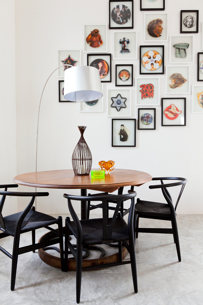 Bohemian dining room in London with white walls, concrete flooring and feature lighting.