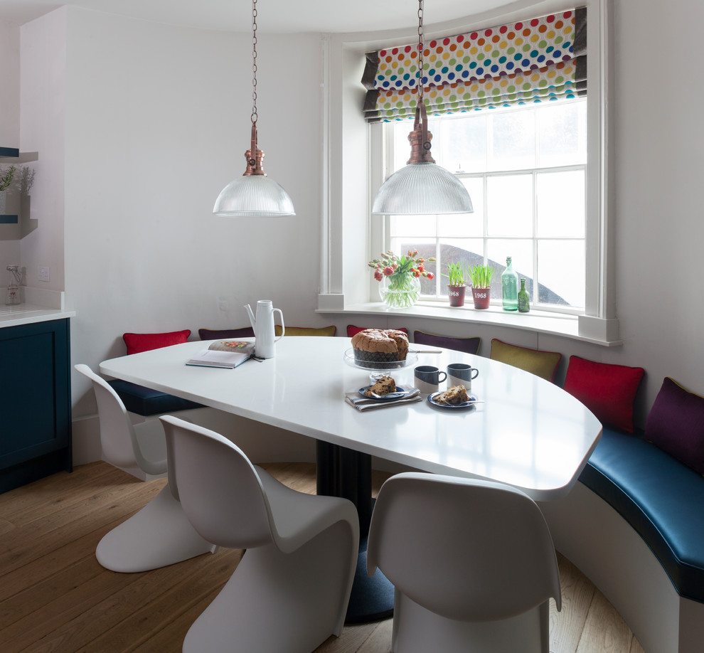 Cette image montre une grande salle à manger ouverte sur la cuisine traditionnelle avec un sol en bois brun et un mur blanc.