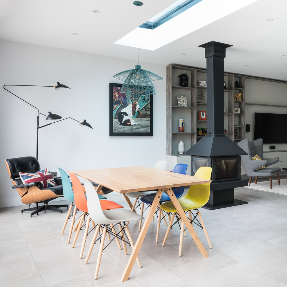 Contemporary open plan dining room in London with white walls, a wood burning stove, a metal fireplace surround and feature lighting.