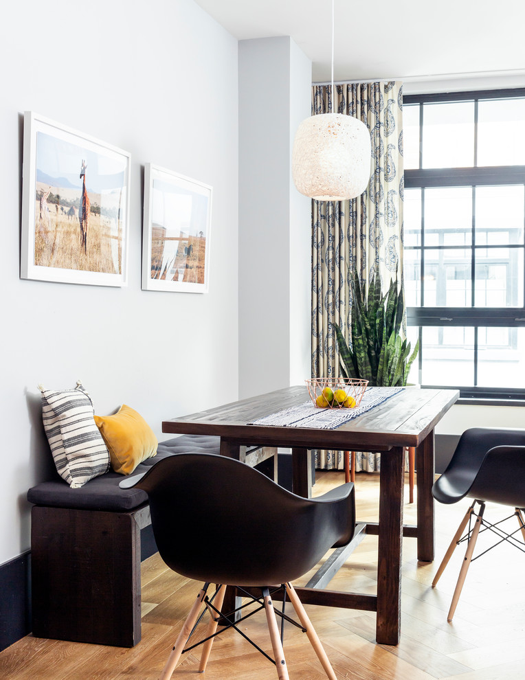 Exemple d'une salle à manger ouverte sur le salon éclectique avec un sol en bois brun et un mur gris.