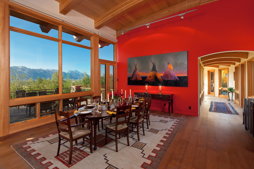 Foto di una sala da pranzo aperta verso il soggiorno rustica con pareti rosse e pavimento in legno massello medio