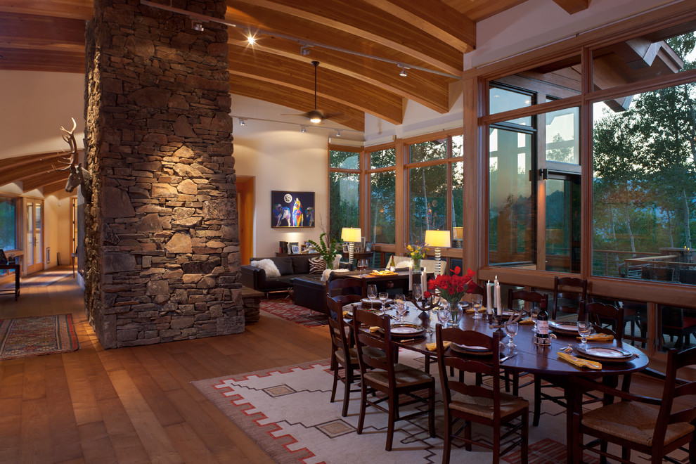 Mountain style medium tone wood floor great room photo in Other with white walls and a stone fireplace