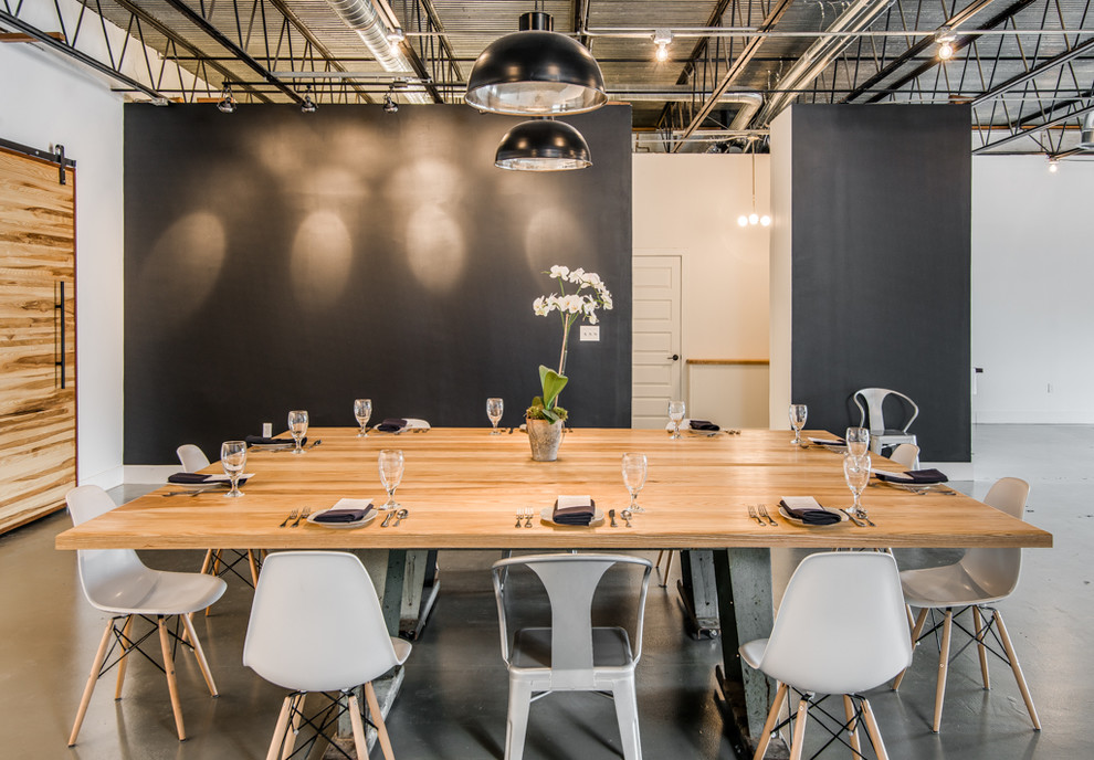 Ispirazione per un'ampia sala da pranzo aperta verso il soggiorno industriale con pareti nere e pavimento in cemento