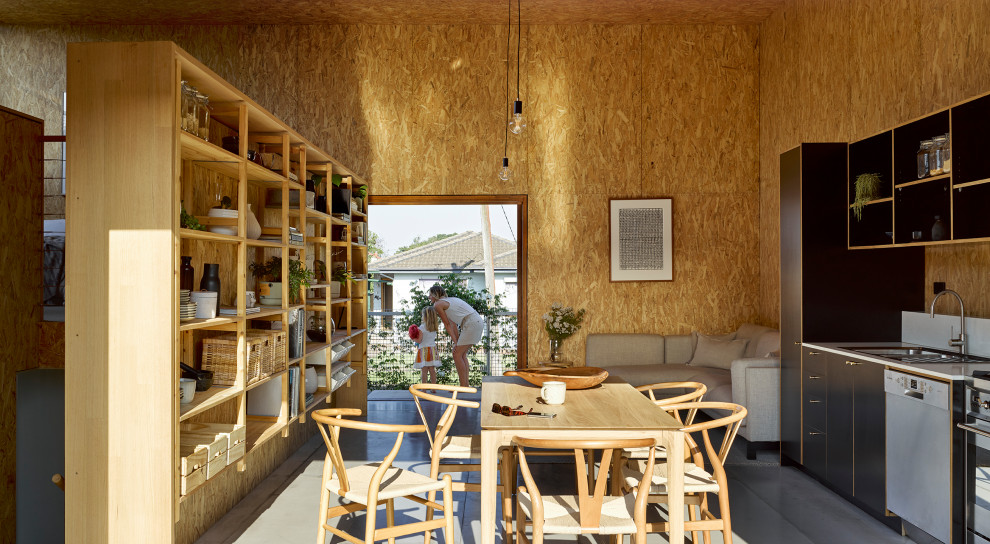 Esempio di una sala da pranzo aperta verso la cucina industriale con pareti marroni, pavimento in cemento, pavimento grigio, soffitto in legno e pareti in legno