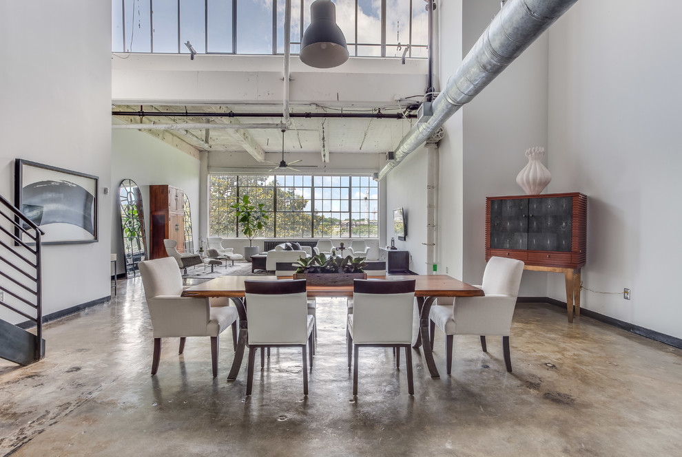 Immagine di una sala da pranzo industriale con pareti bianche e pavimento in cemento