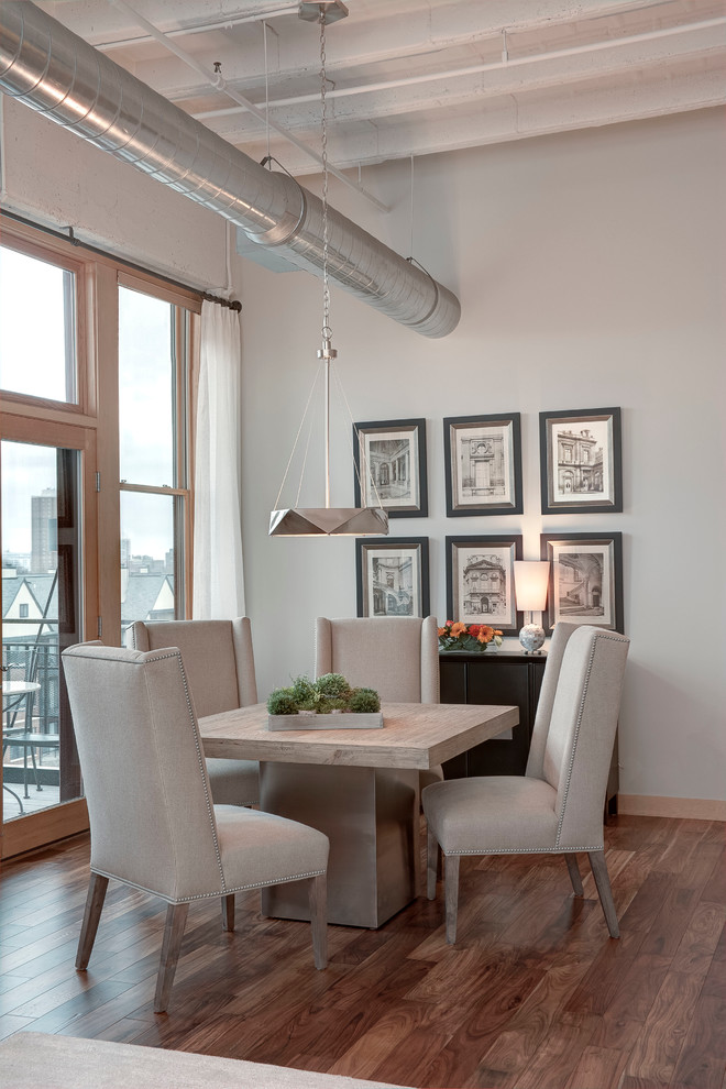 Cette image montre une petite salle à manger urbaine avec un mur gris, un sol en bois brun, aucune cheminée, un sol marron et éclairage.
