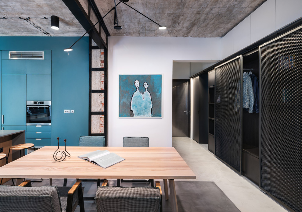 Immagine di una sala da pranzo aperta verso la cucina industriale di medie dimensioni con pareti bianche e pavimento grigio