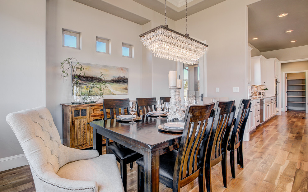 Exemple d'une salle à manger ouverte sur le salon chic de taille moyenne avec un mur beige, un sol en bois brun, une cheminée standard, un manteau de cheminée en pierre et un sol marron.