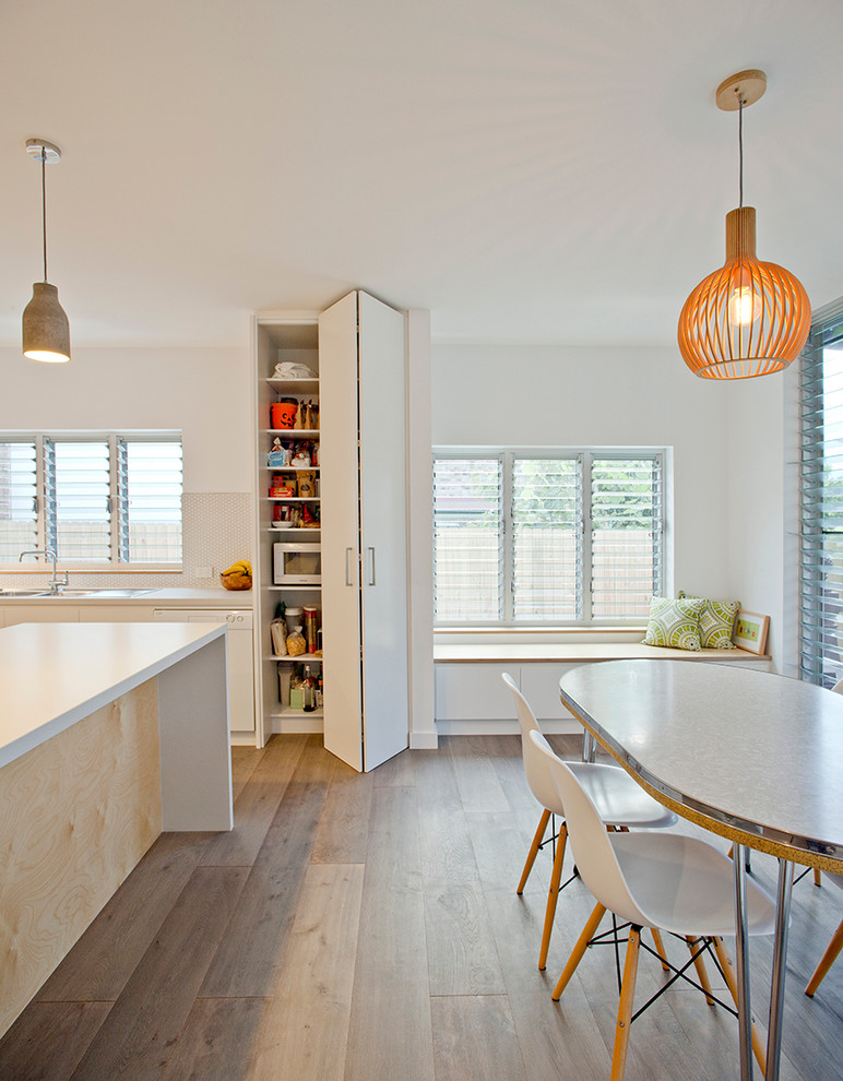 Imagen de comedor contemporáneo sin chimenea con paredes blancas y suelo de madera en tonos medios
