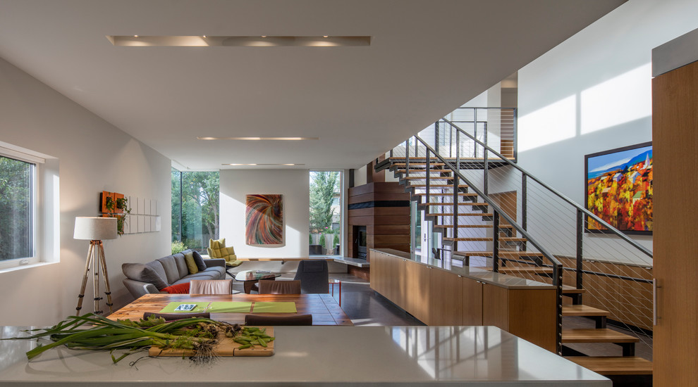 Источник вдохновения для домашнего уюта: гостиная-столовая в стиле модернизм с белыми стенами, бетонным полом, угловым камином, фасадом камина из дерева и серым полом