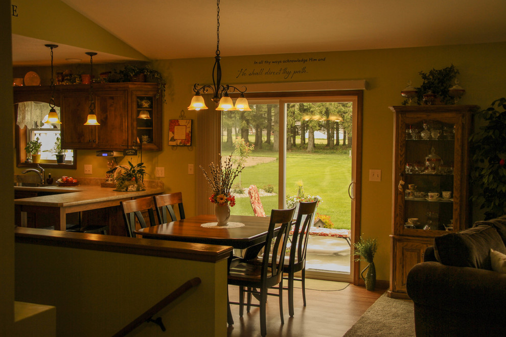 Idées déco pour une salle à manger ouverte sur la cuisine classique de taille moyenne avec un mur vert, sol en stratifié, aucune cheminée et un sol marron.
