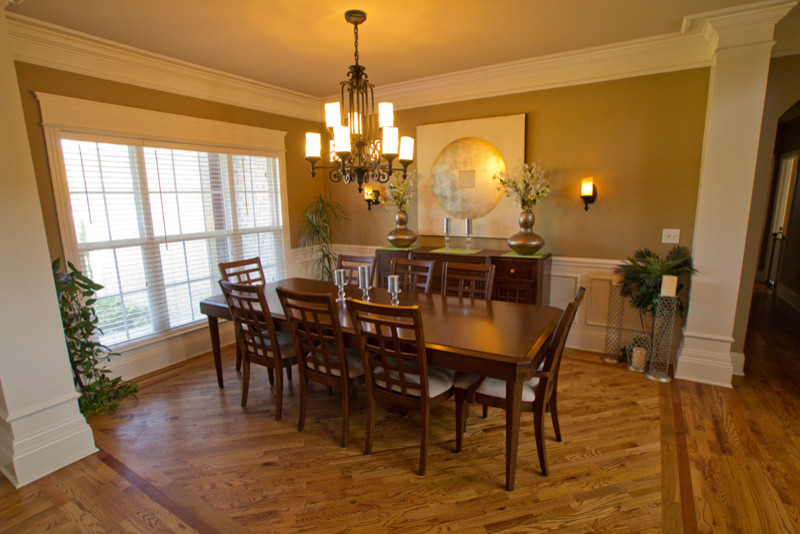 Mid-sized elegant medium tone wood floor enclosed dining room photo in Nashville with green walls
