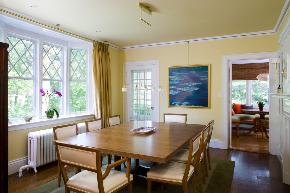 Ejemplo de comedor clásico con paredes amarillas, suelo de madera oscura y cortinas