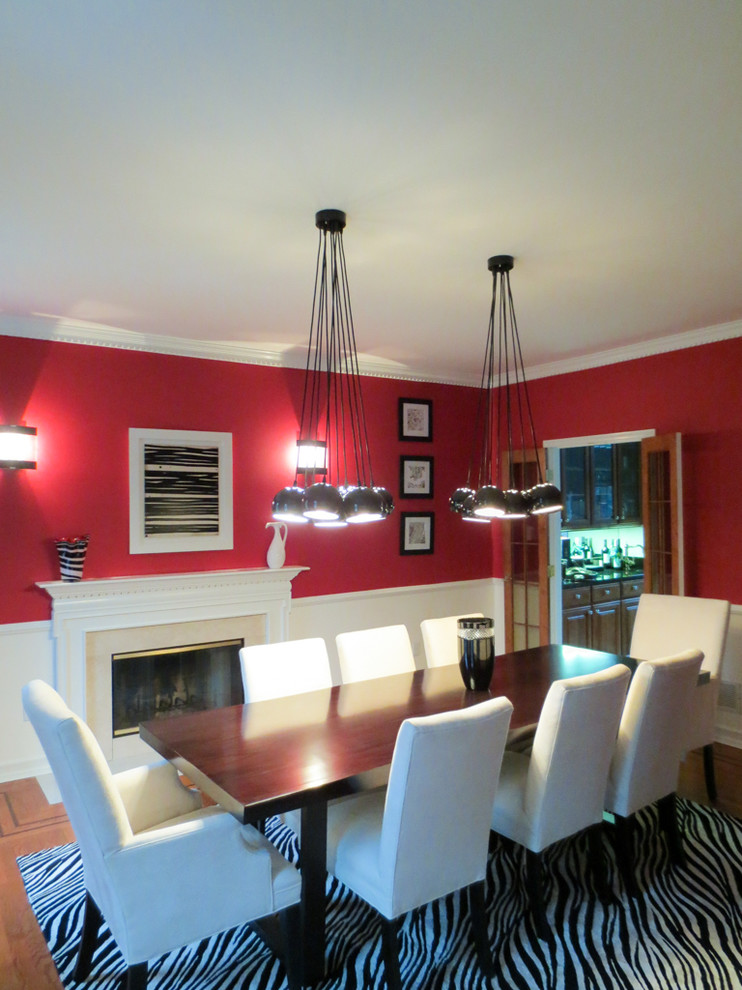 Immagine di una grande sala da pranzo classica chiusa con pareti rosse, pavimento in legno massello medio, camino classico, cornice del camino in pietra e pavimento marrone