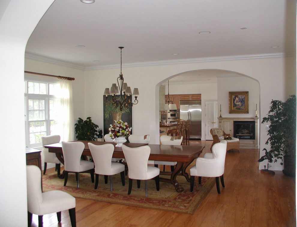 Imagen de comedor de cocina de estilo americano grande con paredes blancas, suelo de madera en tonos medios y marco de chimenea de madera