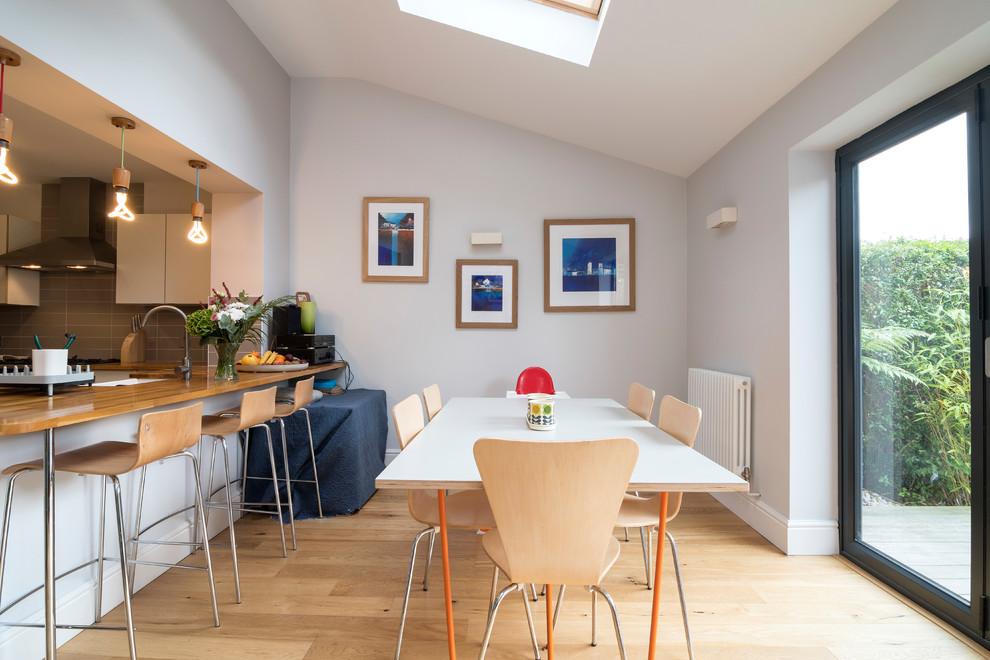 Moderne Wohnküche mit grauer Wandfarbe, hellem Holzboden und beigem Boden in Sonstige