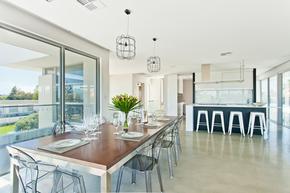 Immagine di una sala da pranzo aperta verso il soggiorno contemporanea con pareti bianche, pavimento in cemento e nessun camino