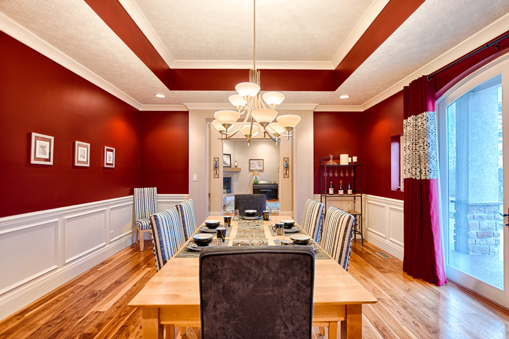 Aménagement d'une grande salle à manger contemporaine fermée avec un mur rouge et parquet clair.