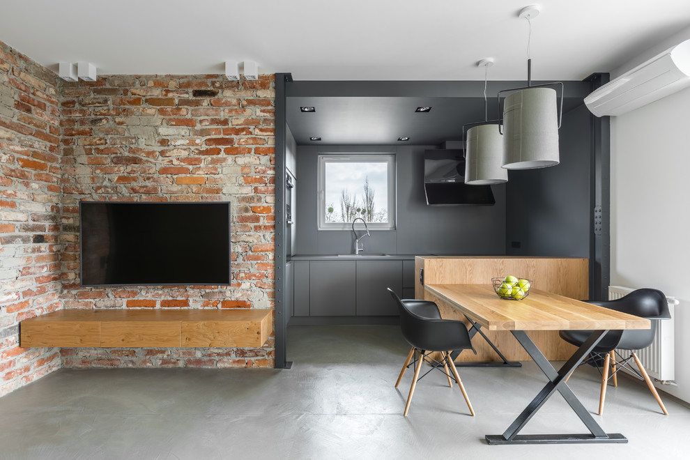 Aménagement d'une salle à manger ouverte sur le salon industrielle avec un mur gris, sol en béton ciré et un sol gris.