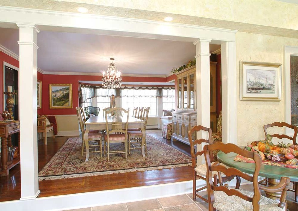 Immagine di una grande sala da pranzo aperta verso il soggiorno tradizionale con pareti rosse, pavimento in legno massello medio, nessun camino e pavimento marrone