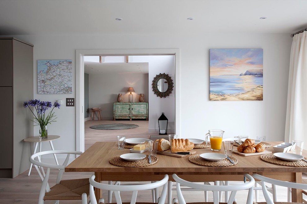 Cette photo montre une salle à manger ouverte sur la cuisine bord de mer de taille moyenne avec un mur blanc et un sol en vinyl.