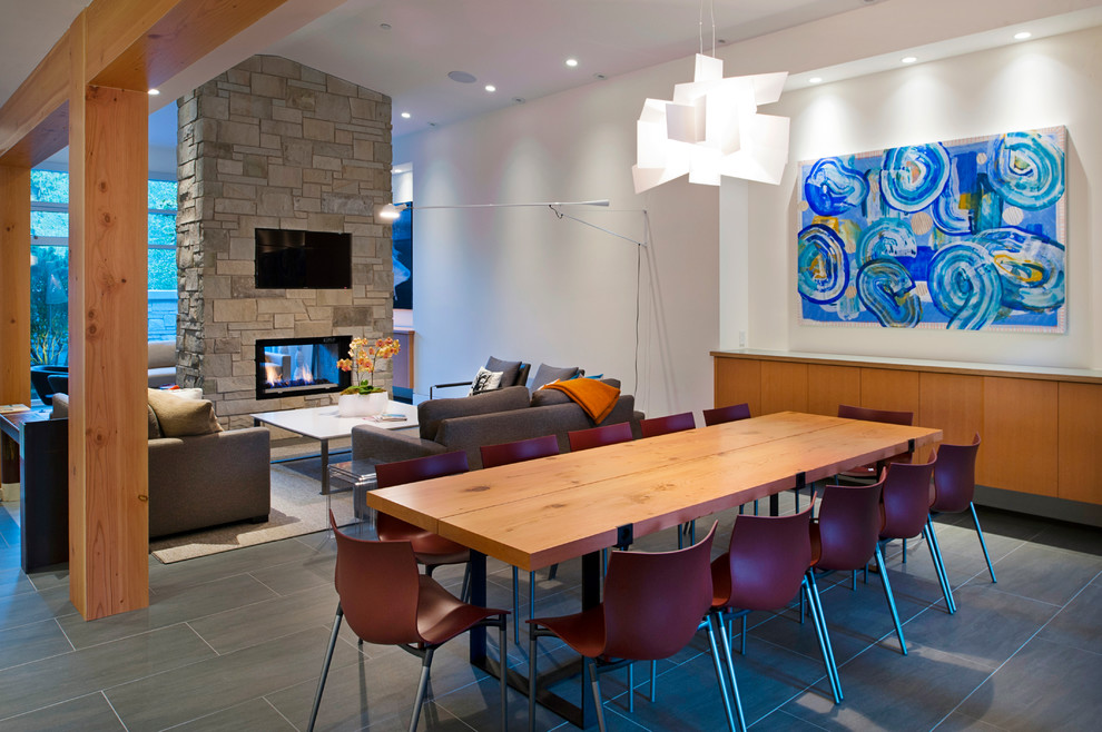 Idee per una sala da pranzo aperta verso il soggiorno design con camino bifacciale e pavimento in ardesia