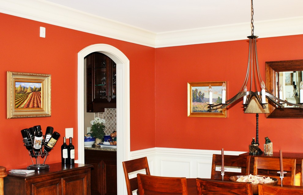 Cette photo montre une salle à manger chic avec un mur rouge.