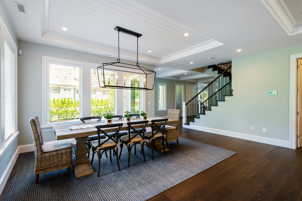 This is an example of an expansive rural open plan dining room in Vancouver with grey walls, medium hardwood flooring, a standard fireplace, a stone fireplace surround and brown floors.
