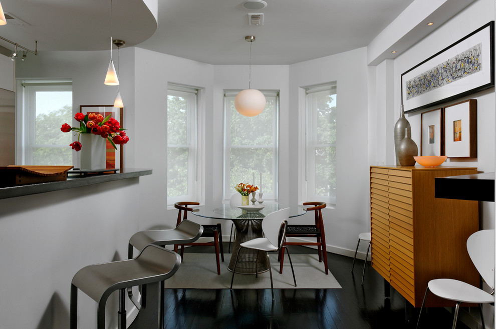 Réalisation d'une salle à manger ouverte sur la cuisine design avec un mur blanc et parquet foncé.