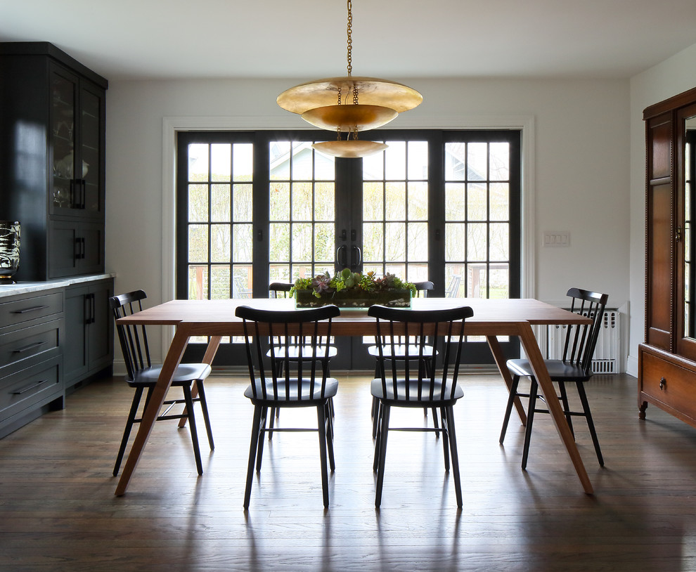 Cette photo montre une salle à manger ouverte sur la cuisine tendance de taille moyenne avec un mur blanc, un sol en bois brun et un sol gris.