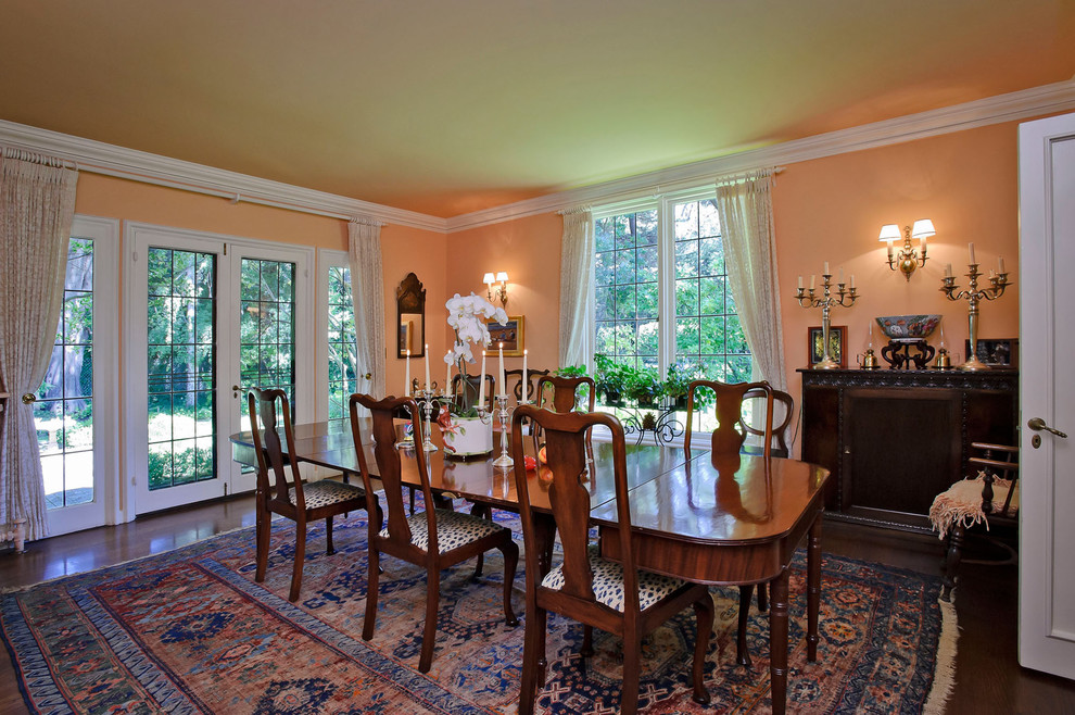 Idée de décoration pour une salle à manger tradition avec un mur orange et parquet foncé.