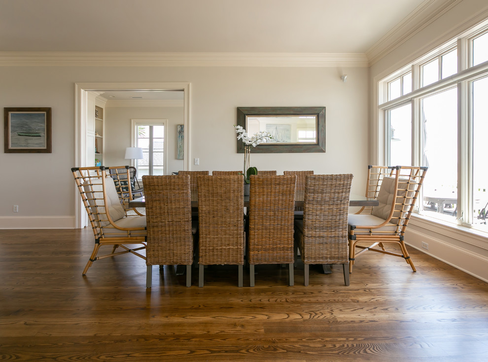 Cette image montre une très grande salle à manger ouverte sur le salon marine avec un mur gris, un sol en bois brun et un sol marron.