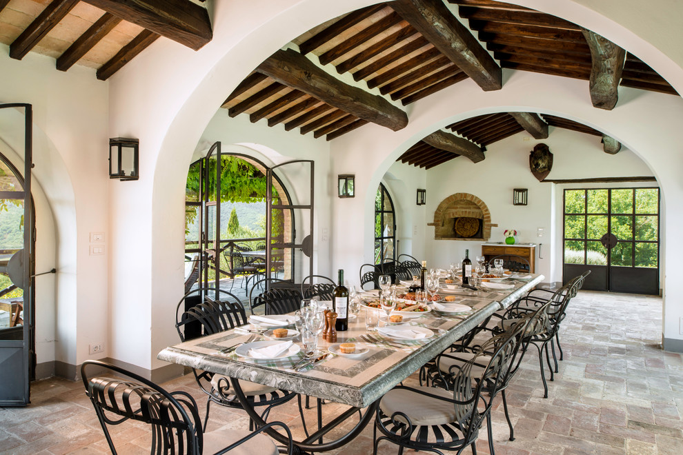 Foto di una sala da pranzo mediterranea con pareti bianche e pavimento in mattoni