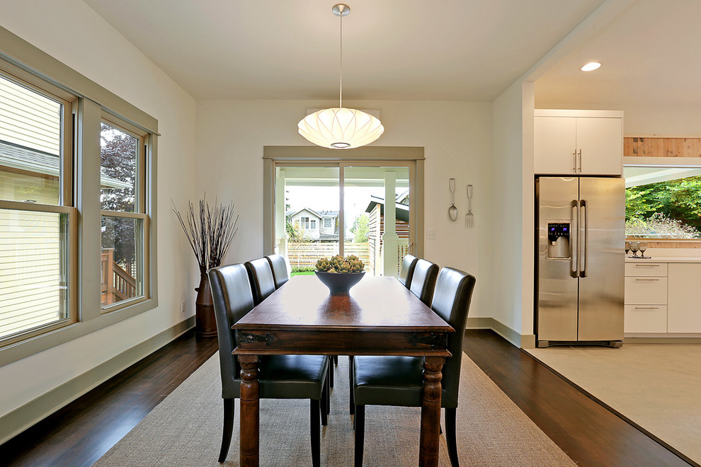 This is an example of a contemporary kitchen/dining room in Seattle with white walls and dark hardwood flooring.