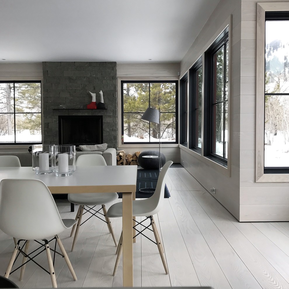 Aménagement d'une grande salle à manger ouverte sur le salon scandinave avec un mur gris, parquet clair, une cheminée standard, un sol gris, un manteau de cheminée en pierre et éclairage.