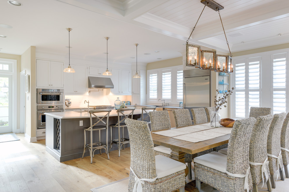 Immagine di una sala da pranzo aperta verso la cucina stile marinaro con pareti beige e parquet chiaro