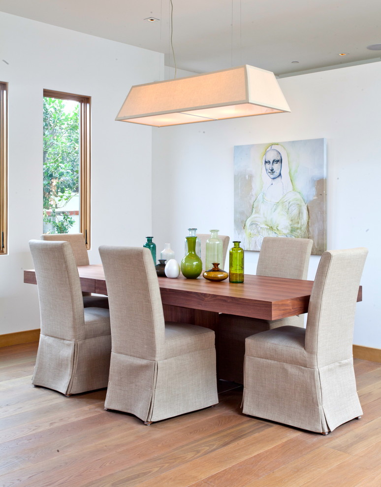 Exemple d'une salle à manger ouverte sur le salon tendance de taille moyenne avec un mur blanc et un sol en bois brun.