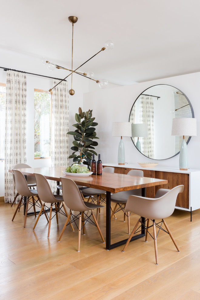 Photo of a medium sized contemporary open plan dining room in Los Angeles with white walls, medium hardwood flooring, no fireplace, brown floors and feature lighting.