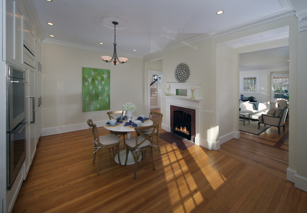 Kleine Klassische Wohnküche mit braunem Holzboden, Kamin, Kaminumrandung aus Backstein, gelber Wandfarbe und gelbem Boden in Boston