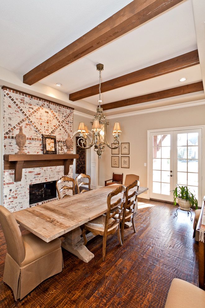 Aménagement d'une salle à manger avec un mur beige, parquet foncé, une cheminée standard et un manteau de cheminée en brique.