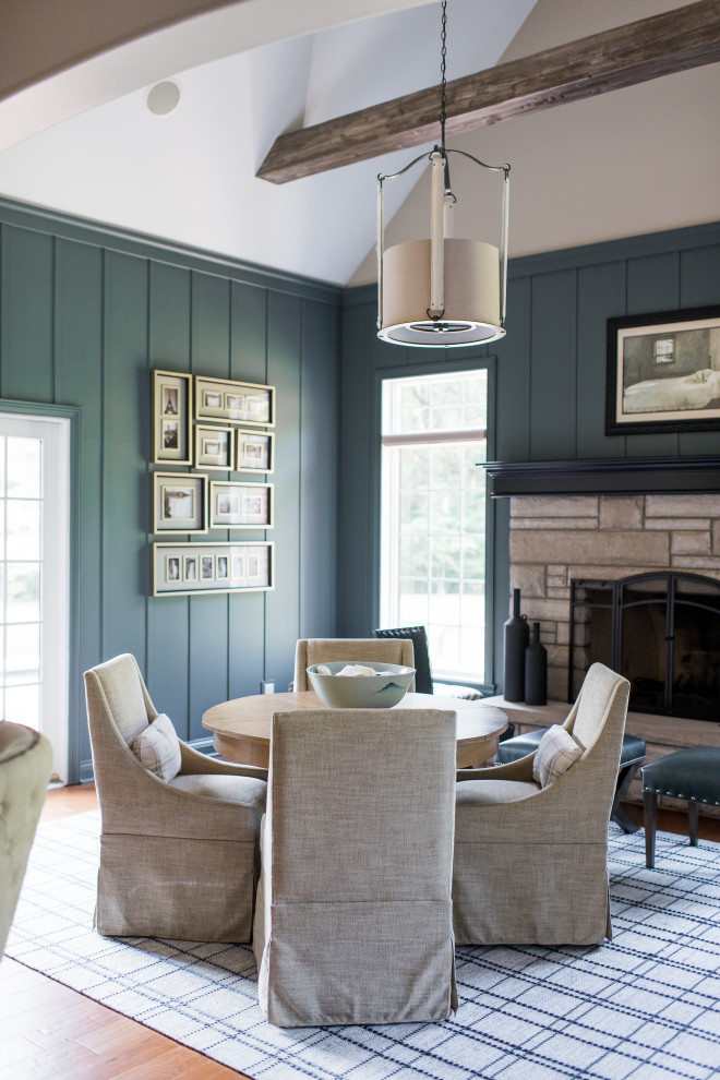 Cette photo montre une salle à manger ouverte sur le salon moderne de taille moyenne avec un mur bleu, un sol en bois brun, une cheminée standard et un manteau de cheminée en brique.