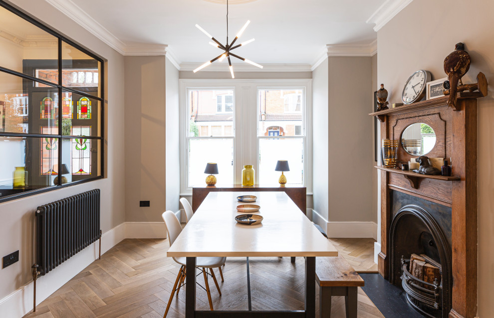 This is an example of a medium sized classic enclosed dining room in London with beige walls, light hardwood flooring, a standard fireplace, a wooden fireplace surround, beige floors and a chimney breast.