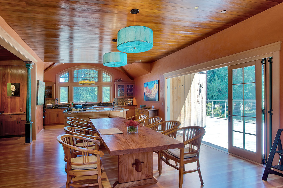 Cette image montre une salle à manger ouverte sur la cuisine rustique de taille moyenne avec un mur orange, un sol en bois brun et aucune cheminée.