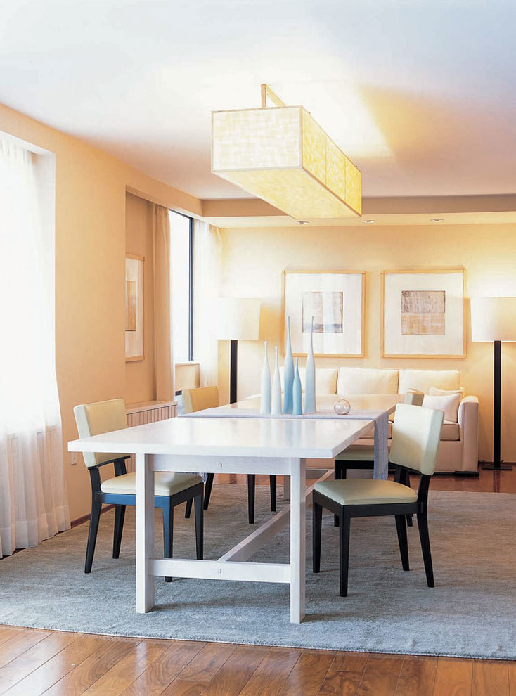 Esempio di una sala da pranzo aperta verso il soggiorno design di medie dimensioni con pareti gialle, pavimento in legno massello medio e nessun camino