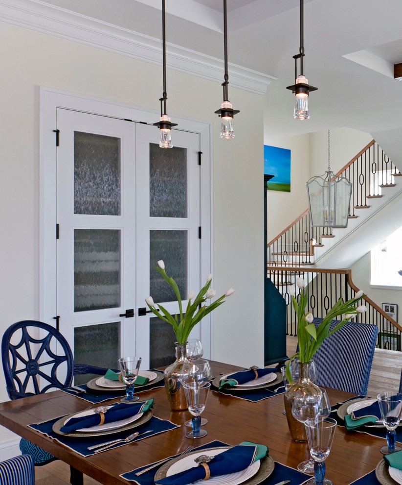 Foto di una sala da pranzo aperta verso il soggiorno stile marinaro di medie dimensioni con pareti bianche, pavimento in legno massello medio e nessun camino