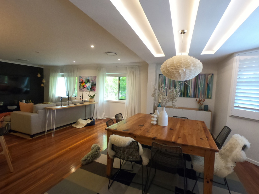 Immagine di una grande sala da pranzo aperta verso il soggiorno moderna con pareti bianche e pavimento in legno massello medio