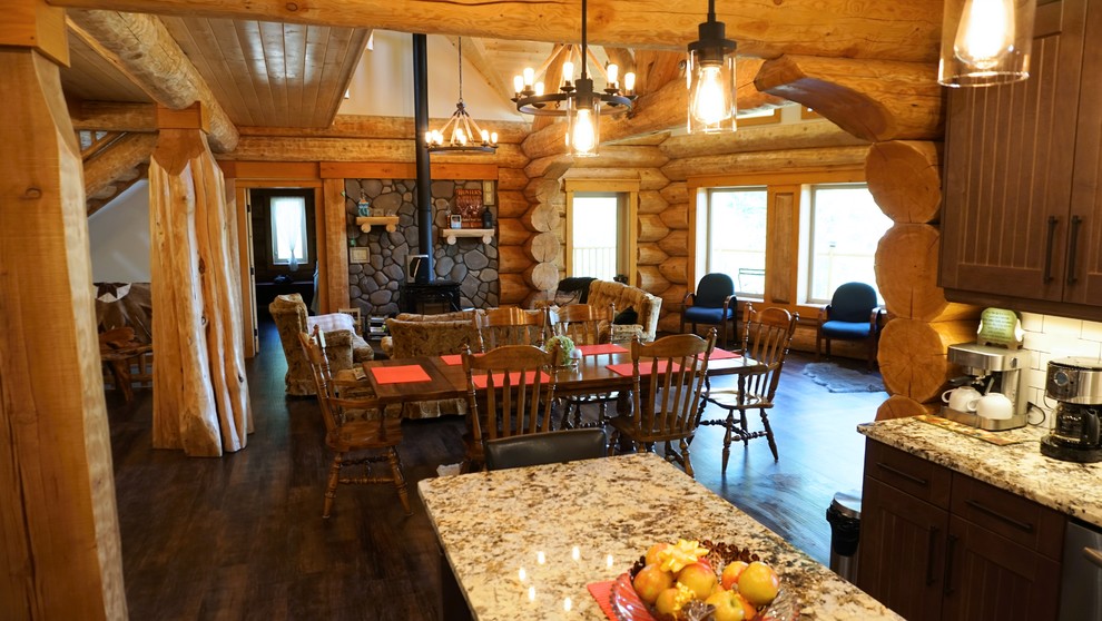Idee per una sala da pranzo aperta verso la cucina rustica di medie dimensioni con pareti beige, parquet scuro, stufa a legna e cornice del camino in pietra