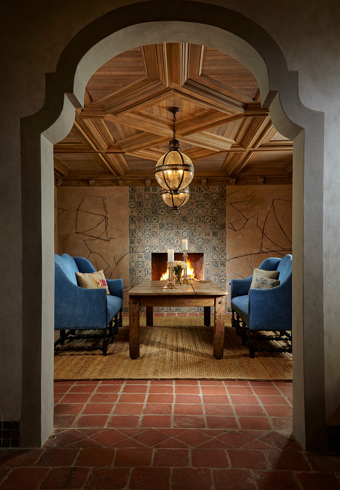 Idée de décoration pour une salle à manger méditerranéenne avec un mur beige, une cheminée standard, un manteau de cheminée en carrelage et un sol rouge.